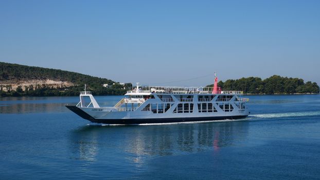 A cruise ship sails through the calm seas of Corfu, Greece, under a clear summer sky.