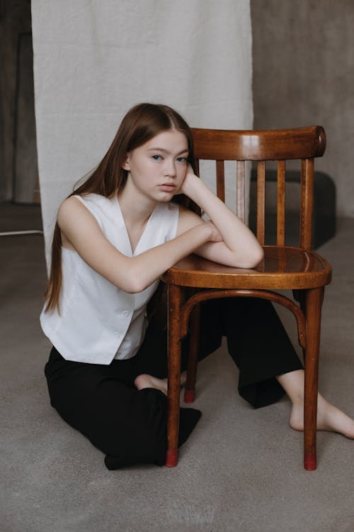 Woman Kneeling Next to a Wooden Chair