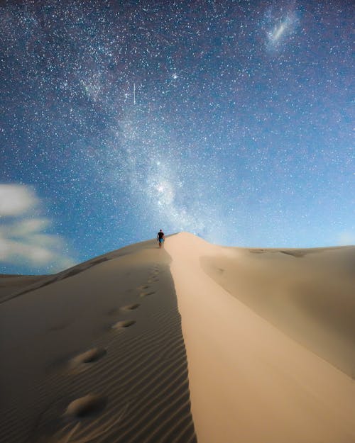 Photo of Person Walking On Desert During Evening