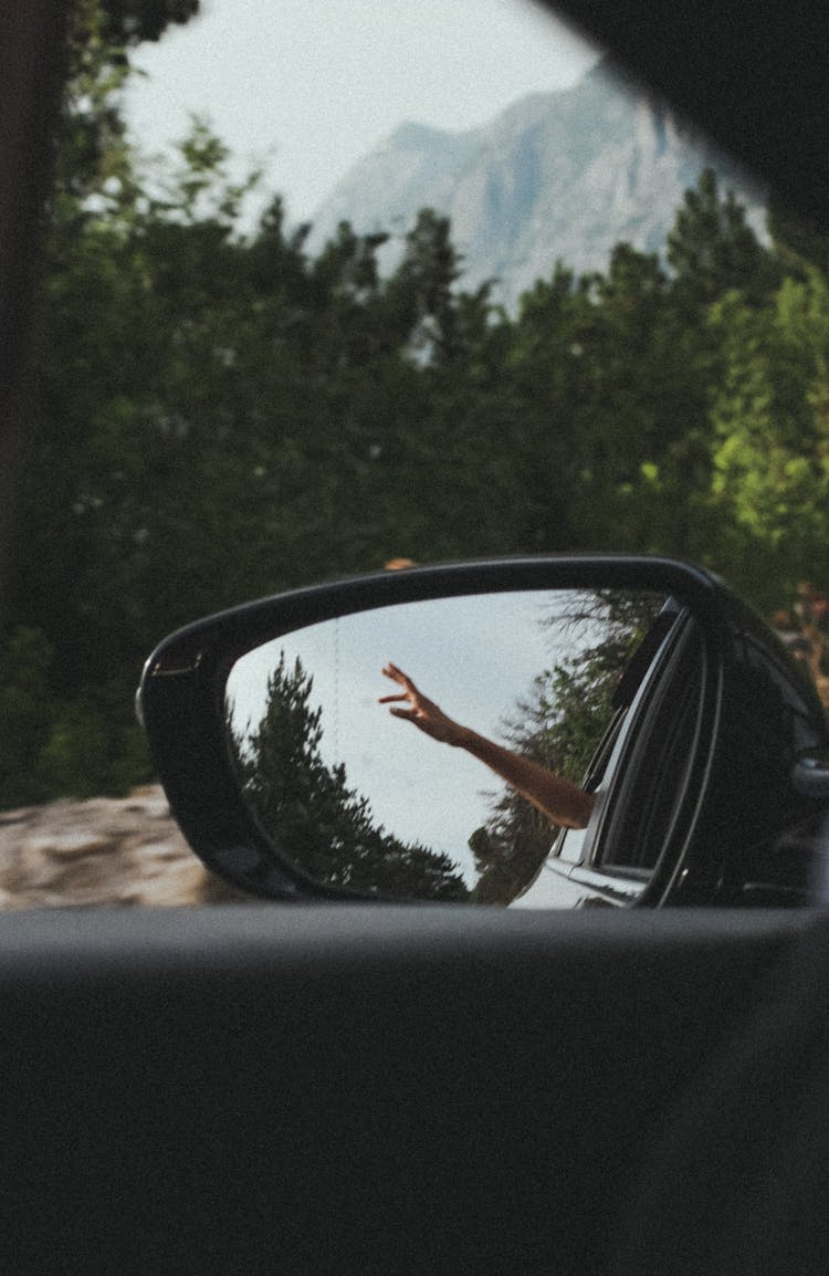 Person's Hand Reflecting On Car Wing Mirror