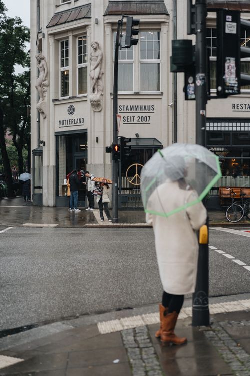Free A person with an umbrella stands on a rainy street in Hamburg near Mutterland. Stock Photo