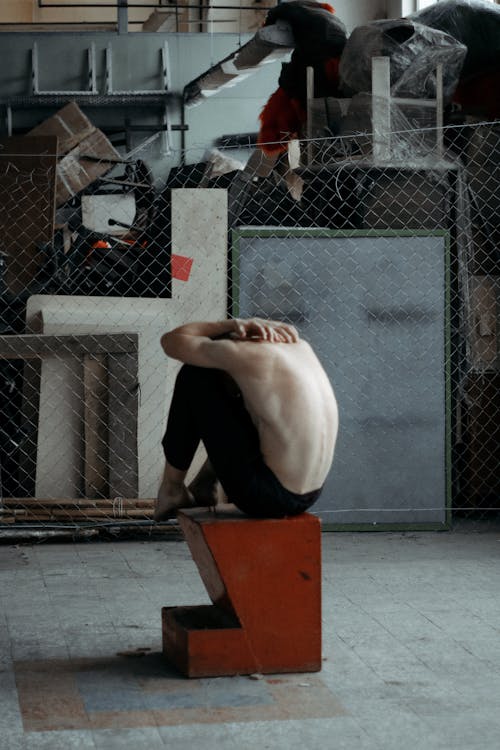 Topless Man Sitting on Brown and Black Block