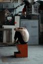 一名男子蜷坐在工业空间的红色街区上，陷入沉思