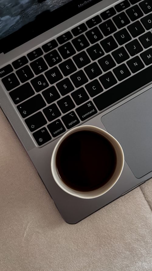 Free Overhead view of a coffee cup on a laptop keyboard, creating a warm and productive atmosphere. Stock Photo