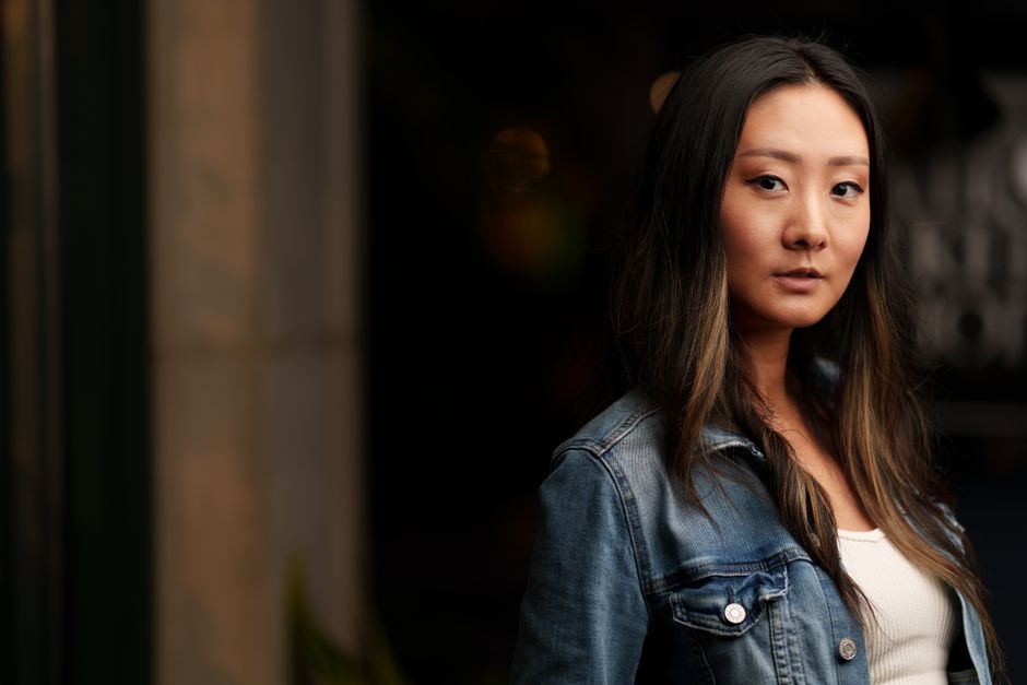A stylish woman poses in a denim jacket in an outdoor setting, showcasing fashion and confidence.
