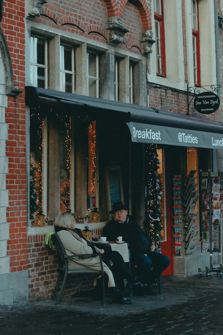 Couple Sitting At Table Outside Store