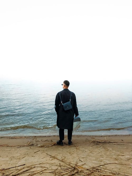 Man in Black Coat on Beach under Fog