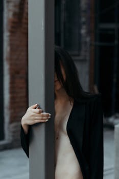 一幅神秘的肖像描绘了一位躲在城市街景中一根杆子后的女人