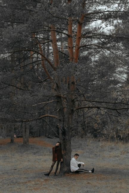 A couple posing under a tree in a peaceful forest setting.