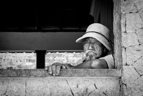 Black and White Photo of an Elderly Man with a Gray Beard Wearing a Hat 