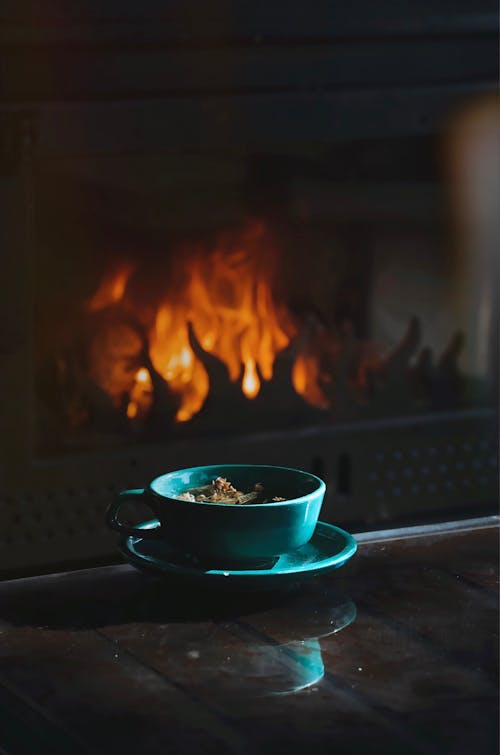 Close-up of a Mug Standing on a Table on the Background of a Fireplace 