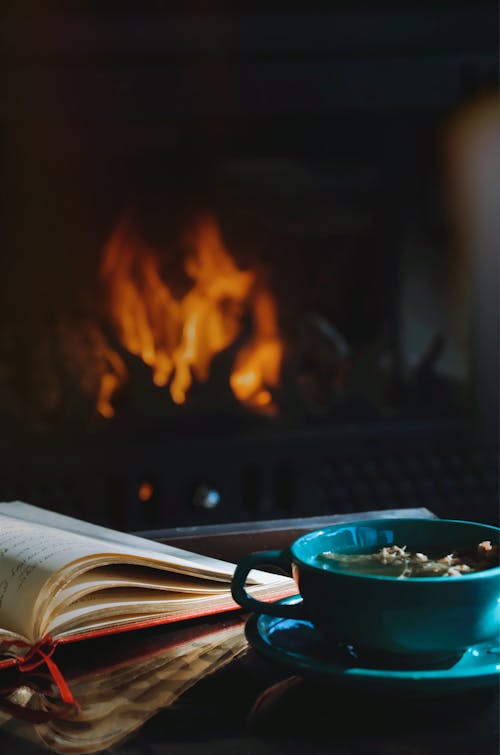 An Opened Book and a Cup of Tea by a Fireplace