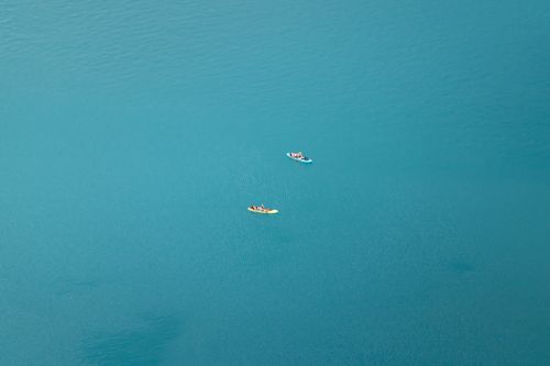Free Aerial shot of two paddleboarders on the turquoise waters of Lake Bled, Slovenia, showcasing serene outdoor adventure. Stock Photo