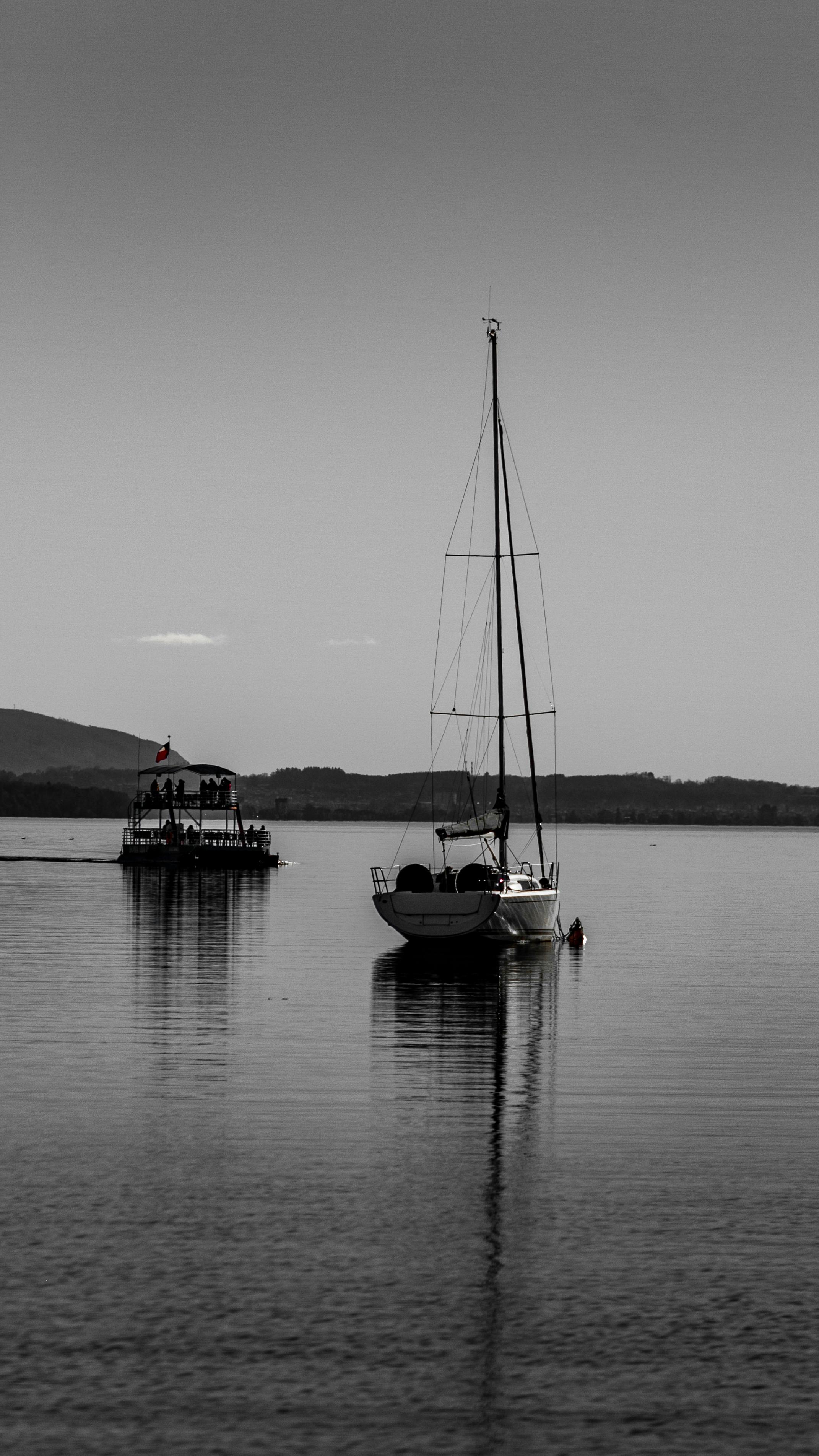 A serene black and white image of a sailboat on Lake Villarrica in Pucon, Araucanía, Chile.