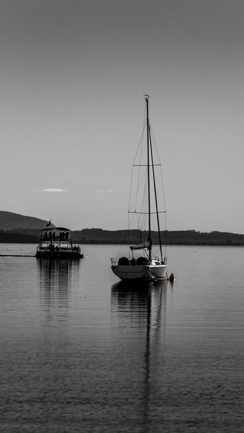 Free A serene black and white image of a sailboat on Lake Villarrica in Pucon, Araucanía, Chile. Stock Photo