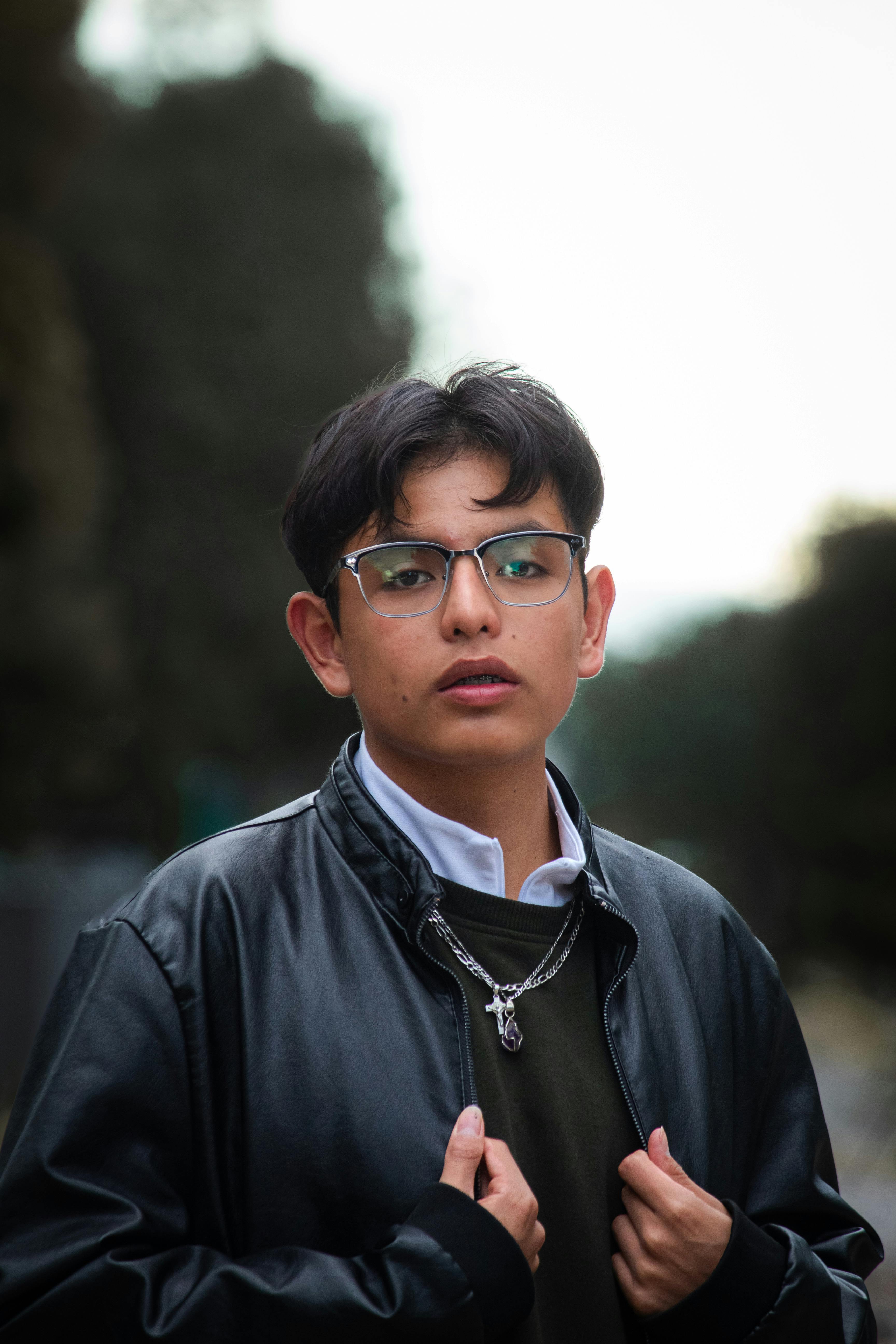 Portrait of a fashionable young man in glasses and leather jacket, outdoors in Texcoco De Mora, Mexico.