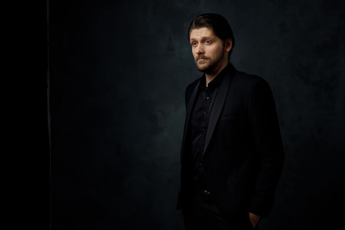 A man in a black suit photographed against a dark background. Photo by Justinas Stanislovaitis on Pexels