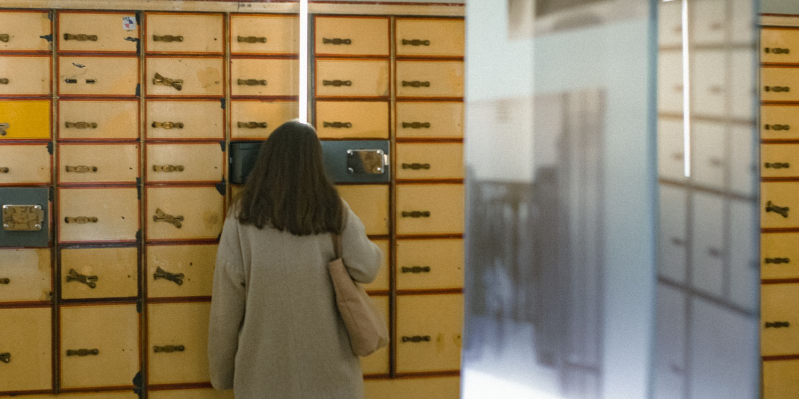 Woman with long brown hair looking at vintage mailboxes in an indoor setting - historic post offices