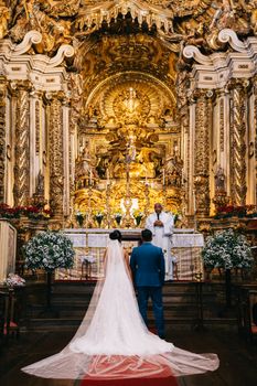 Bride and groom at a stunning golden altar in Tiradentes, Brazil.