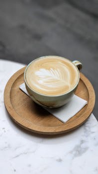 Beautiful cappuccino with leaf latte art on a wooden tray, shot from above.
