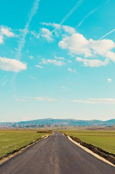 Empty road through scenic countryside with blue sky and clouds. Perfect for wallpapers and travel inspiration.