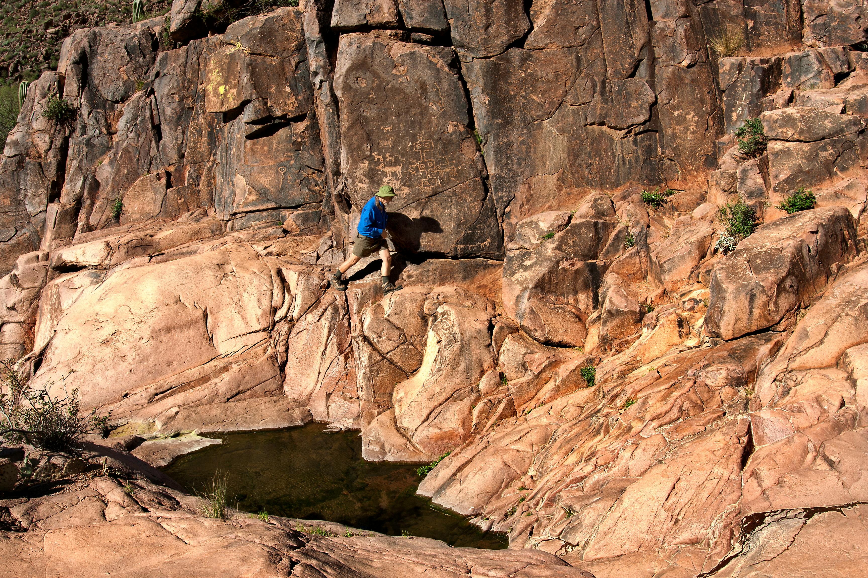 A hiker ascends a rocky path in Arizona's Superstition Mountains, showcasing adventure and rugged landscapes.