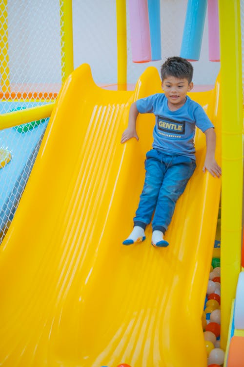 Small Child on the Yellow Slide of the Indoor Playground
