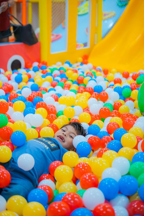 Free A happy child enjoys playing in a vibrant ball pit filled with colorful balls. Stock Photo