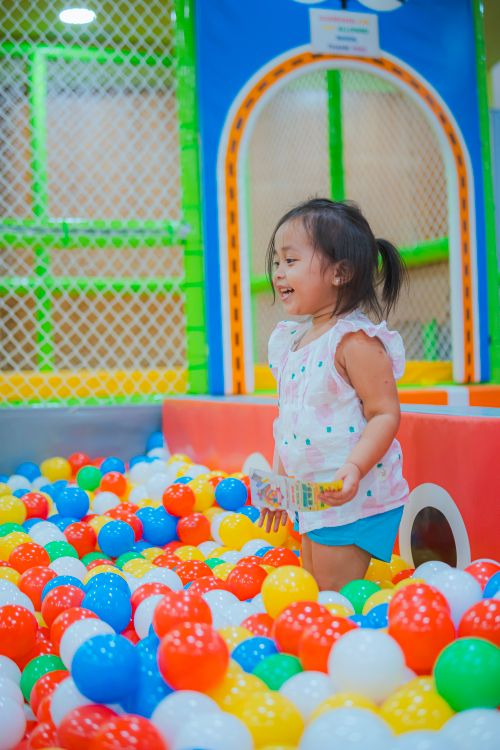 Free Smiling child enjoying vibrant ball pit in indoor playground. Fun and playful scene. Stock Photo