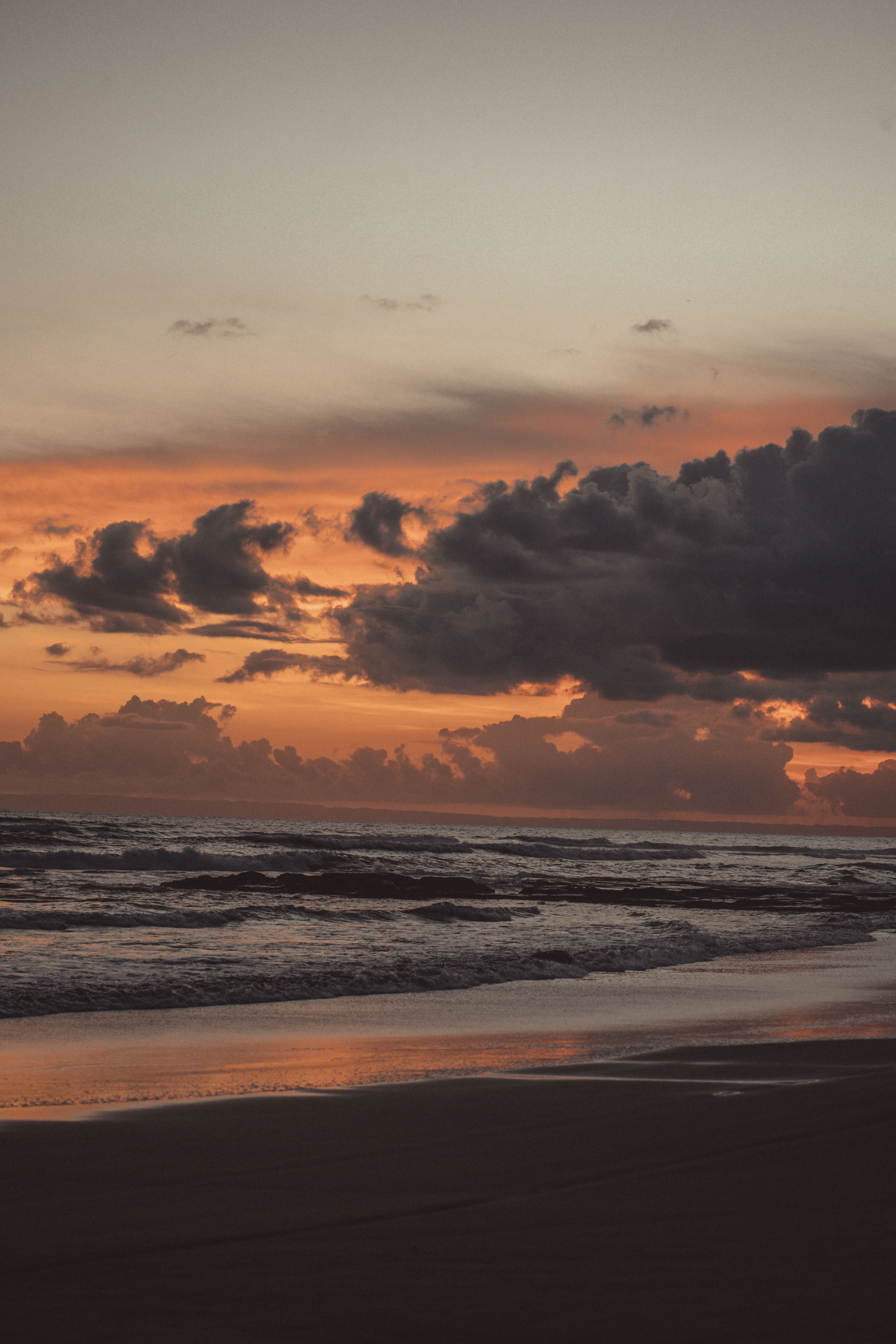 A sunset on the beach with clouds and water · Free Stock Photo