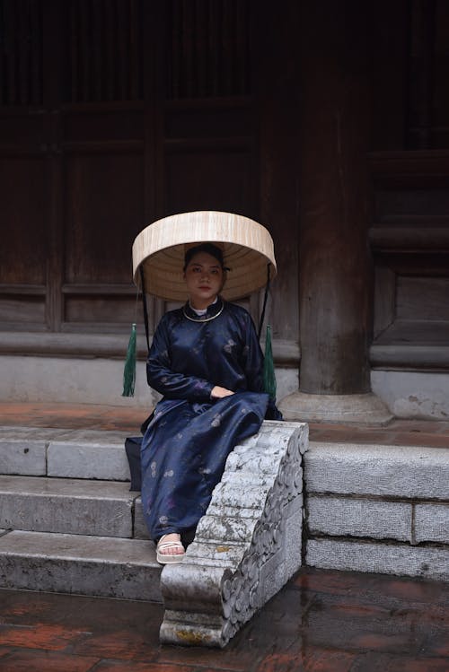 Woman Sitting in Traditional Clothing and Hat