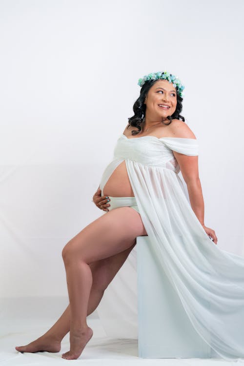 Smiling Pregnant Woman in White Dress