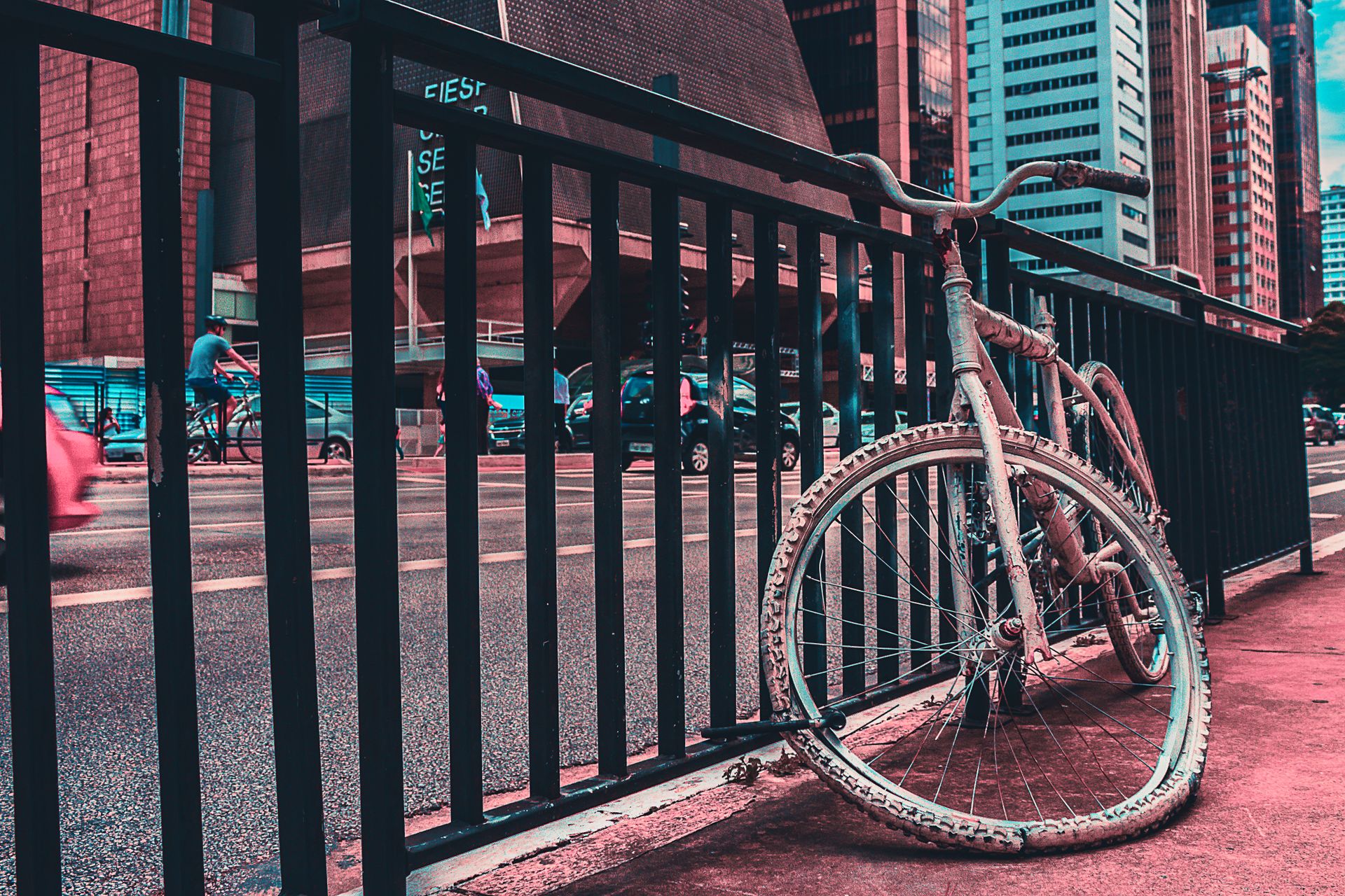 A bicycle leans against a railing in São Paulo's urban setting, showcasing city architecture and street life.