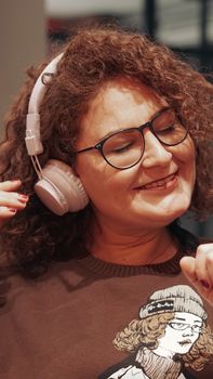 Smiling woman wearing headphones, enjoying music indoors with a relaxed vibe.