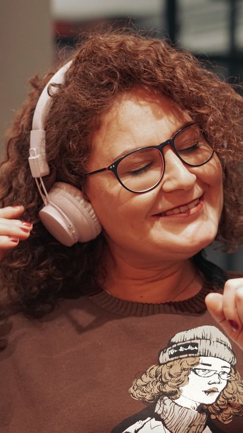 Free Smiling woman wearing headphones, enjoying music indoors with a relaxed vibe. Stock Photo