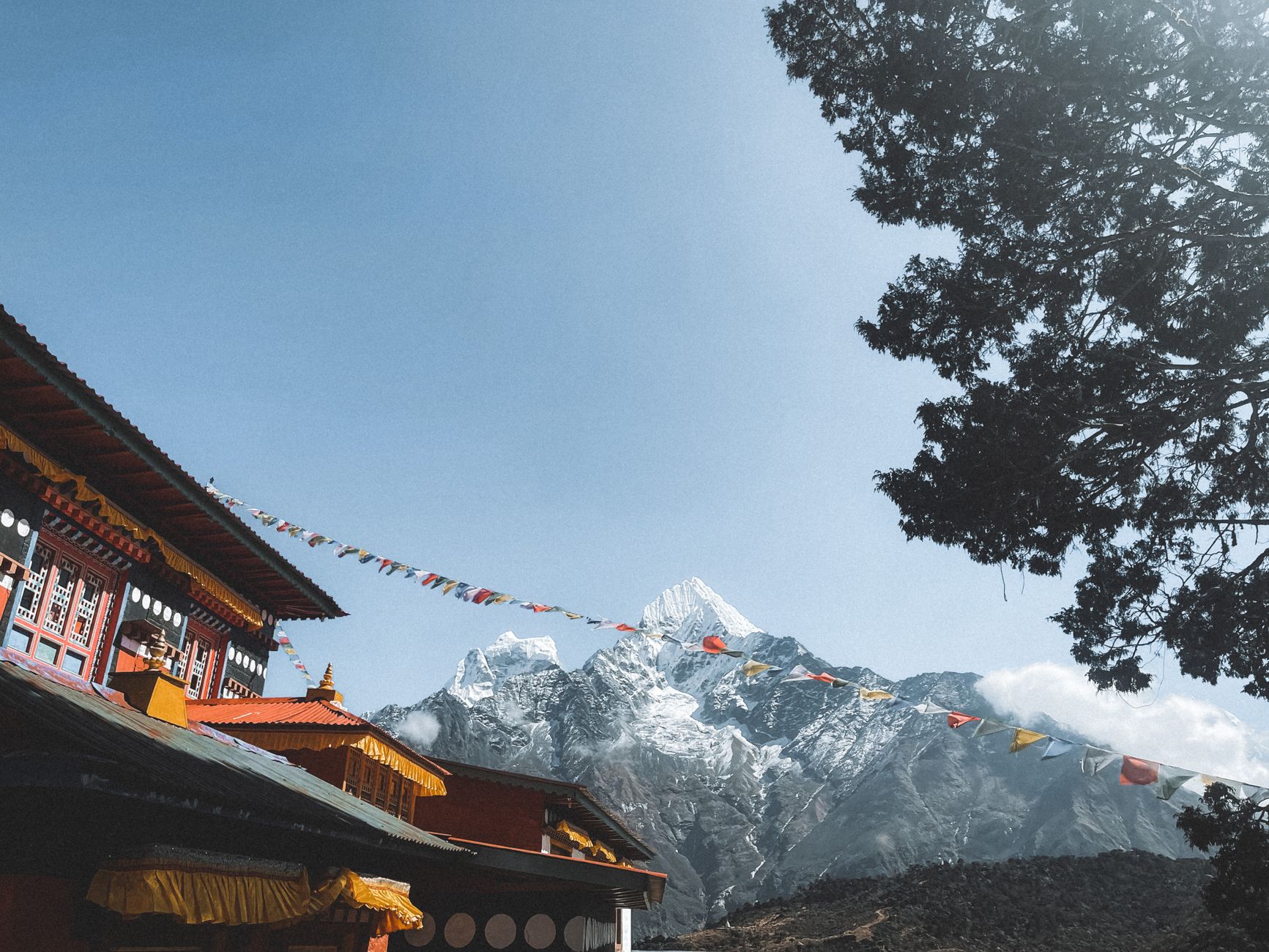 Beautiful Buddhist monastery with Himalayan mountains in Nepal under a clear blue sky.