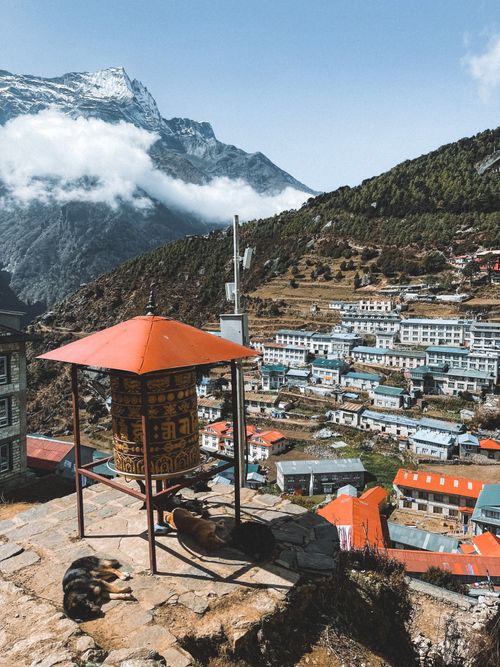 Free Aerial view of Namche Bazaar in Nepal with a traditional prayer wheel and mountain backdrop. Stock Photo