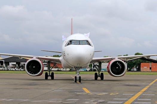 A white Airbus A320 aircraft parked on the tarmac at an airport, ready for departure.