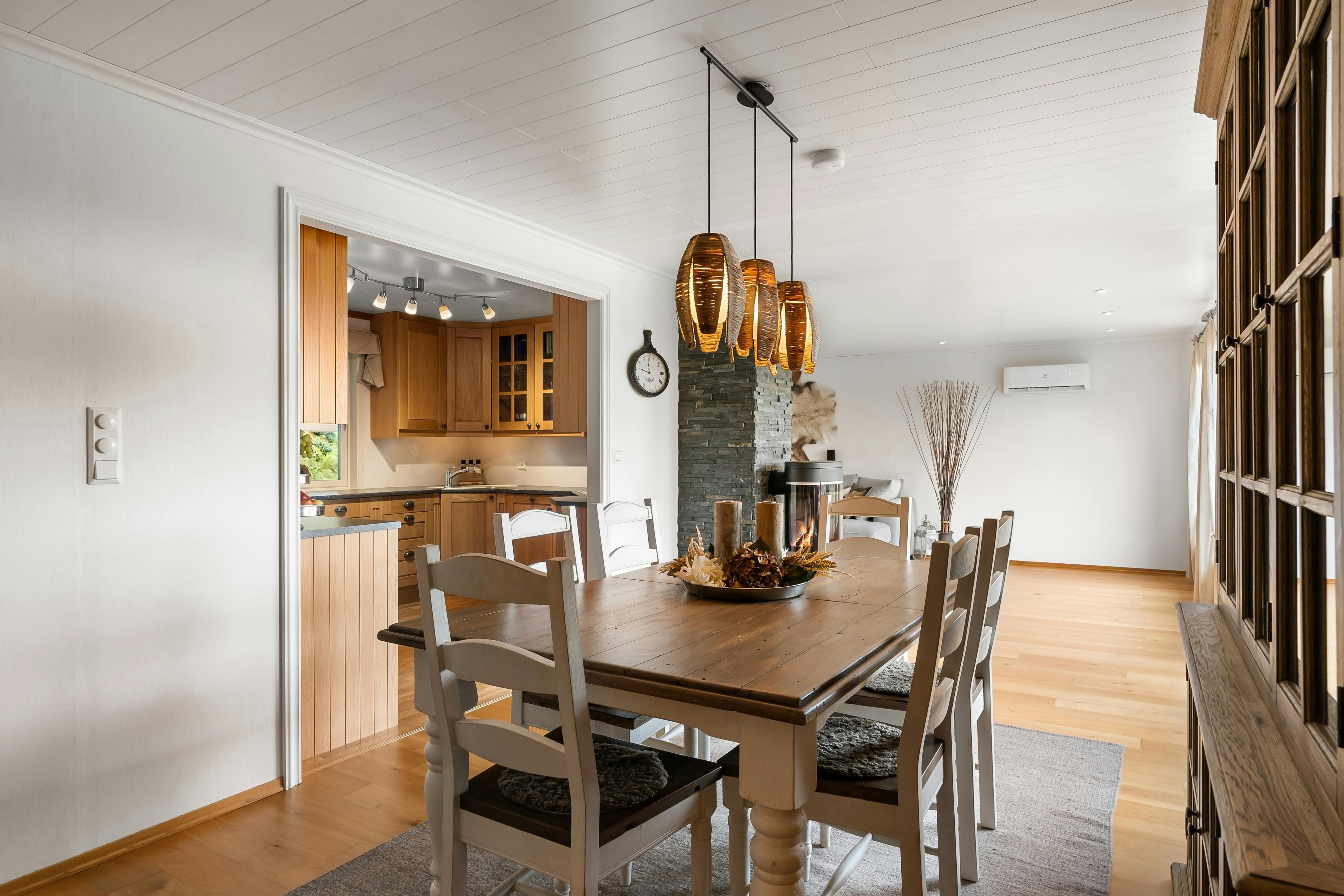 Moderner Essbereich mit drei schwarzen Pendelleuchten über einem Holztisch, warmes Licht und harmonische Anordnung