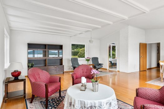 Bright living room with pink armchairs, wooden floors, and picturesque lakeview.