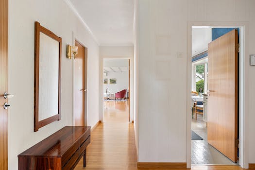 A well-lit modern hallway with open doors leading to a bright living area and garden view.