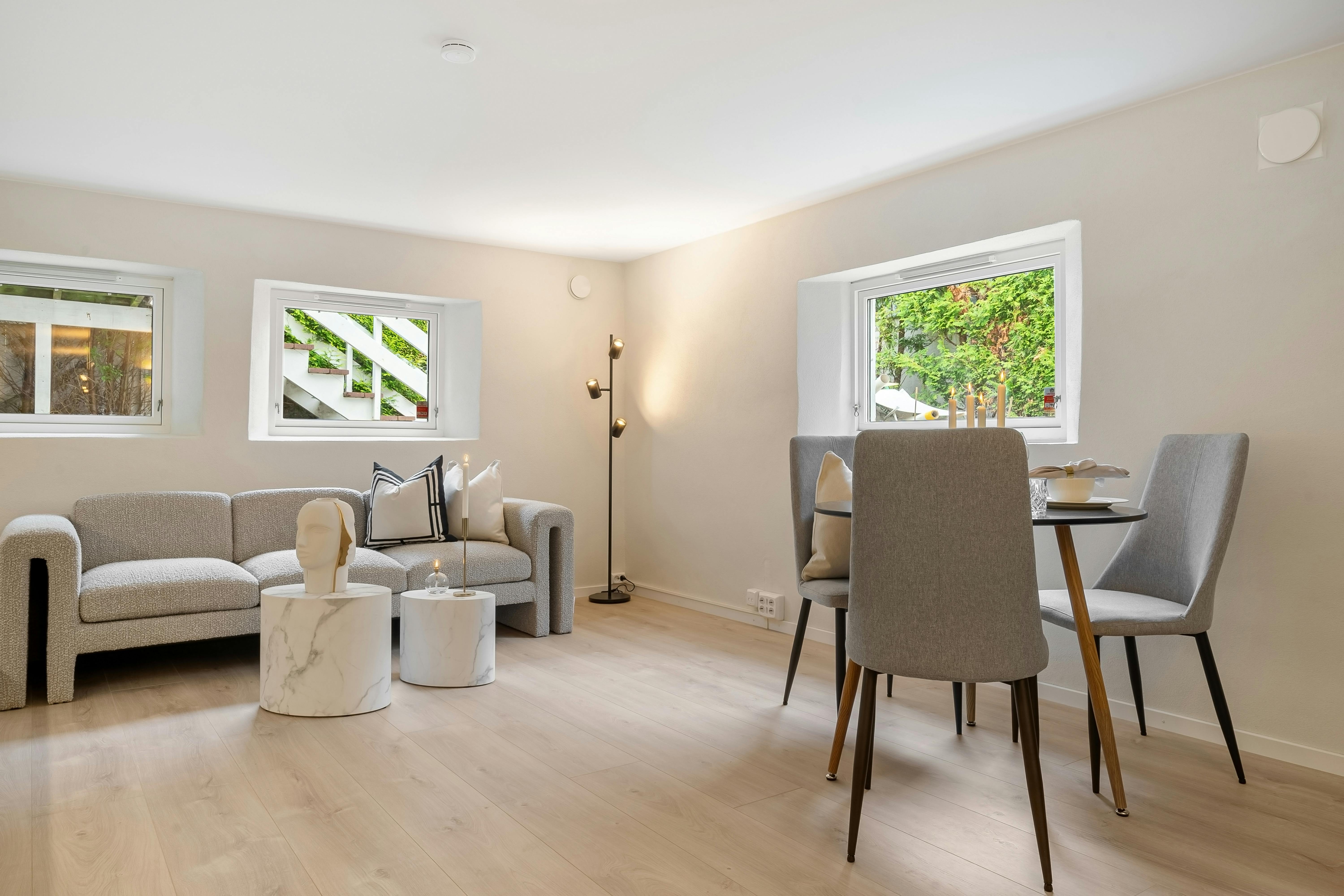 Tapczan na drewnianej podłodze w jasnym salonie, widoczne nóżki i bezpieczne odstępy od ścian