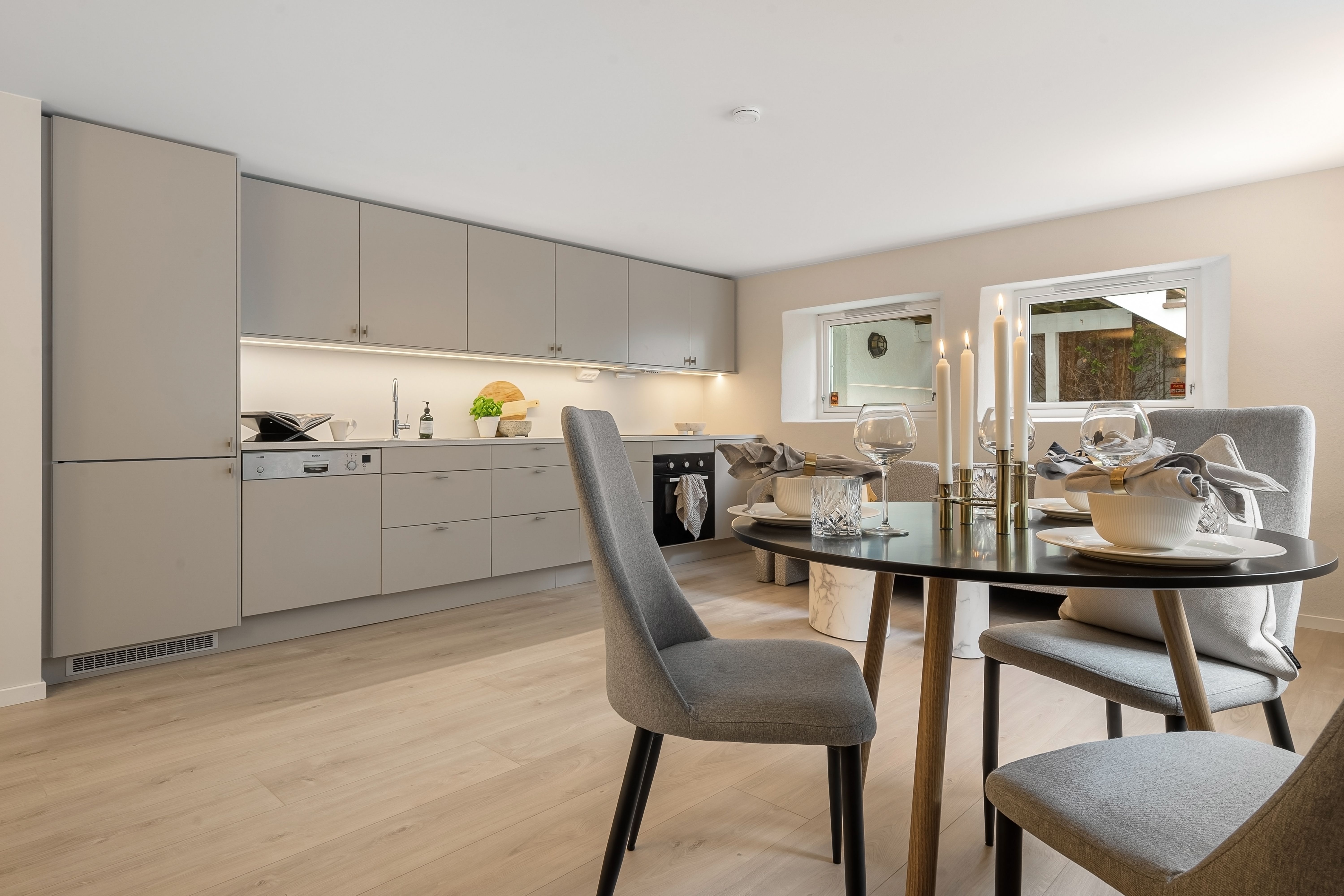 Sleek modern kitchen with elegant table setting and candles, providing a cozy dining atmosphere.