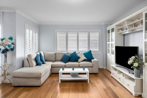 Free Elegant living room featuring a gray sofa, blue accents, and a flat screen TV. Stock Photo