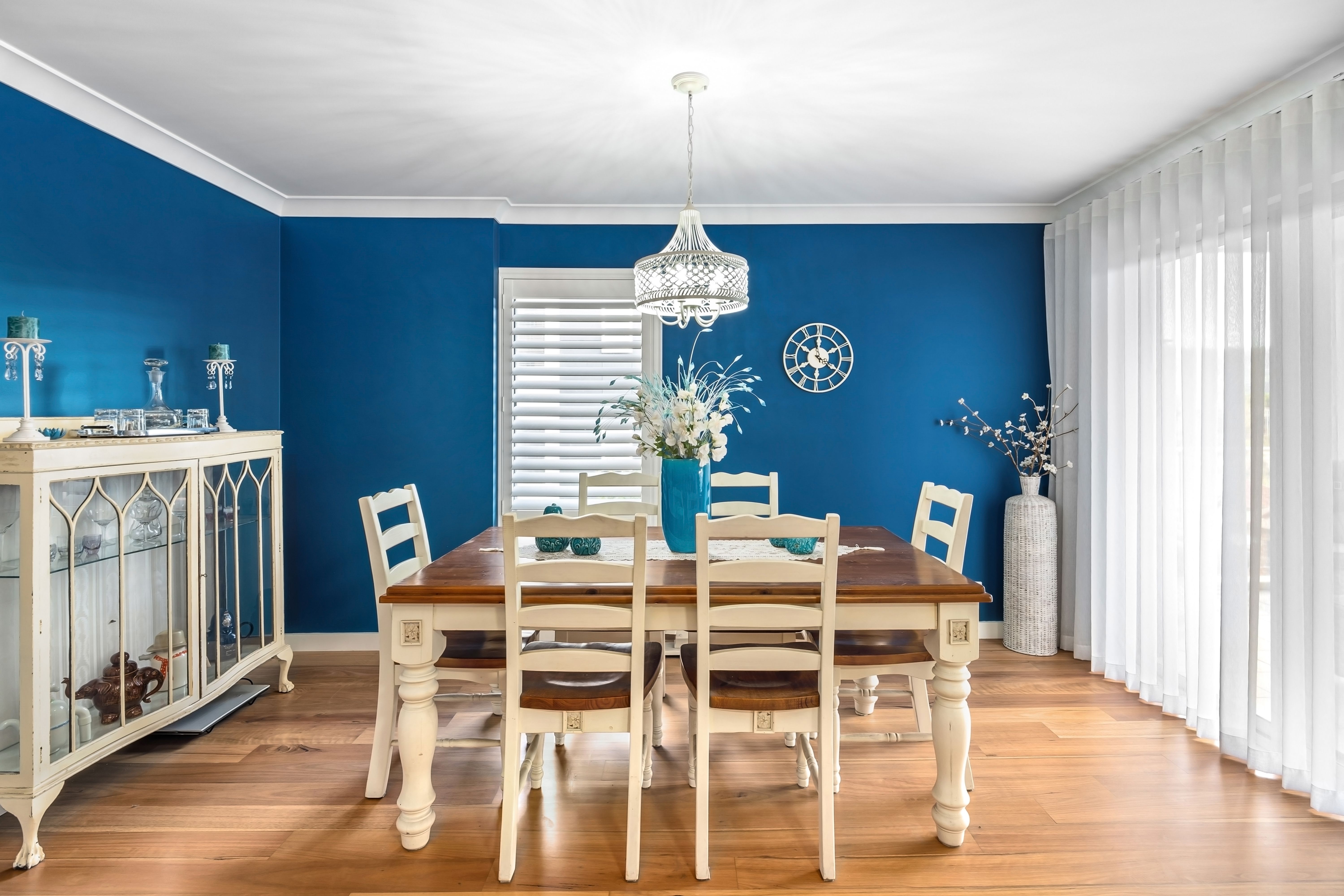 Salle à manger bleue côtière, chaises en bois, lumière naturelle