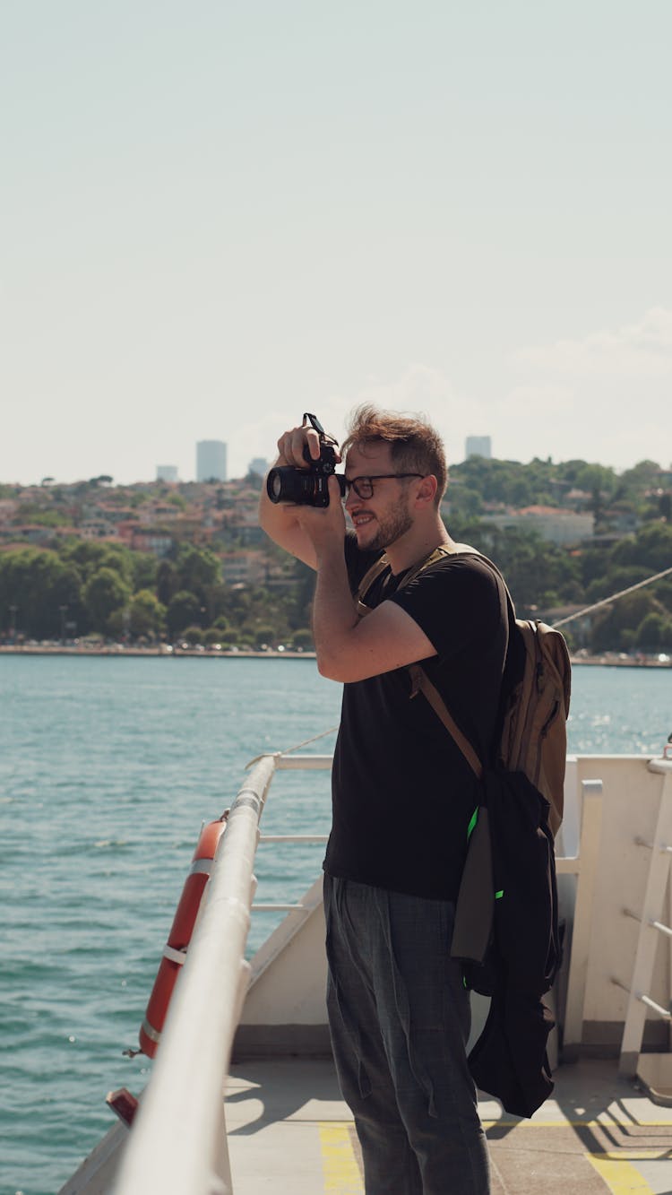 Man With Eyeglasses Taking Photo With Camera On Boat