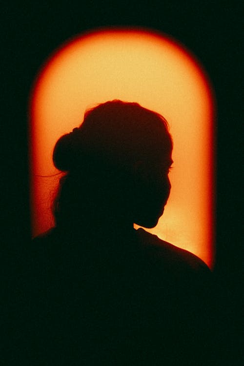 Silhouette of Woman Against Window at Sunset