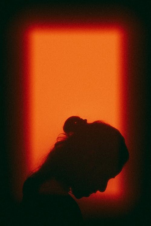 Woman Looking Down Against Orange Light