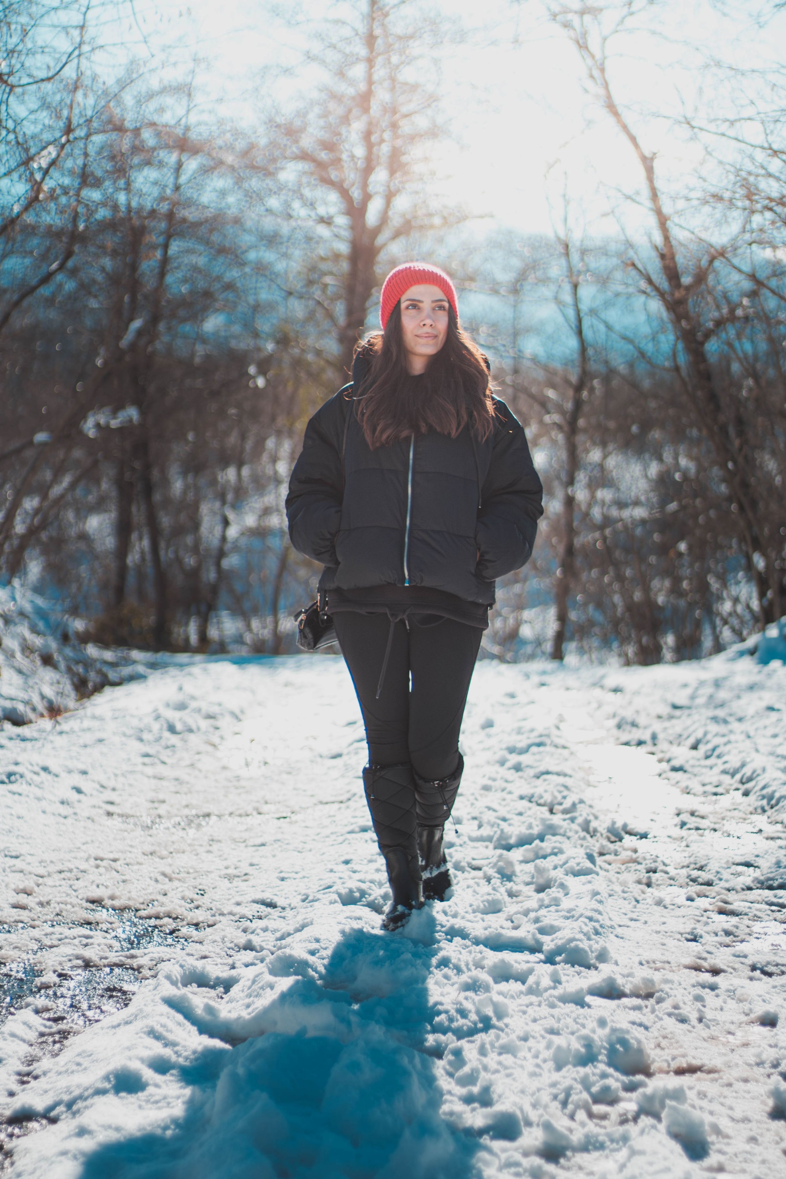 A woman walking through a snowy park in daylight — outdoor light exposure, even on overcast winter days, far exceeds indoor lighting levels