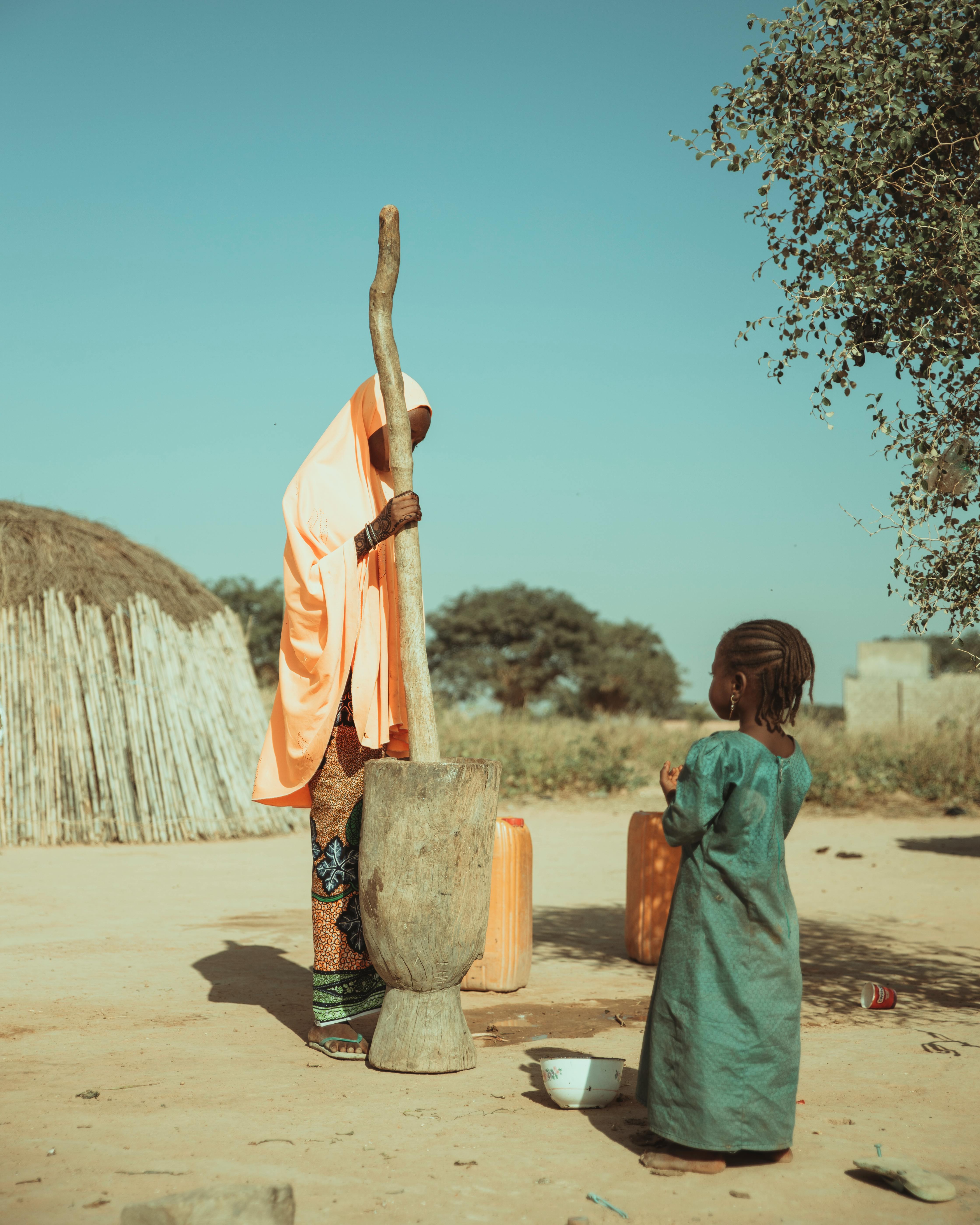 Traditional rural life in Africa with a woman and child interacting outdoors.